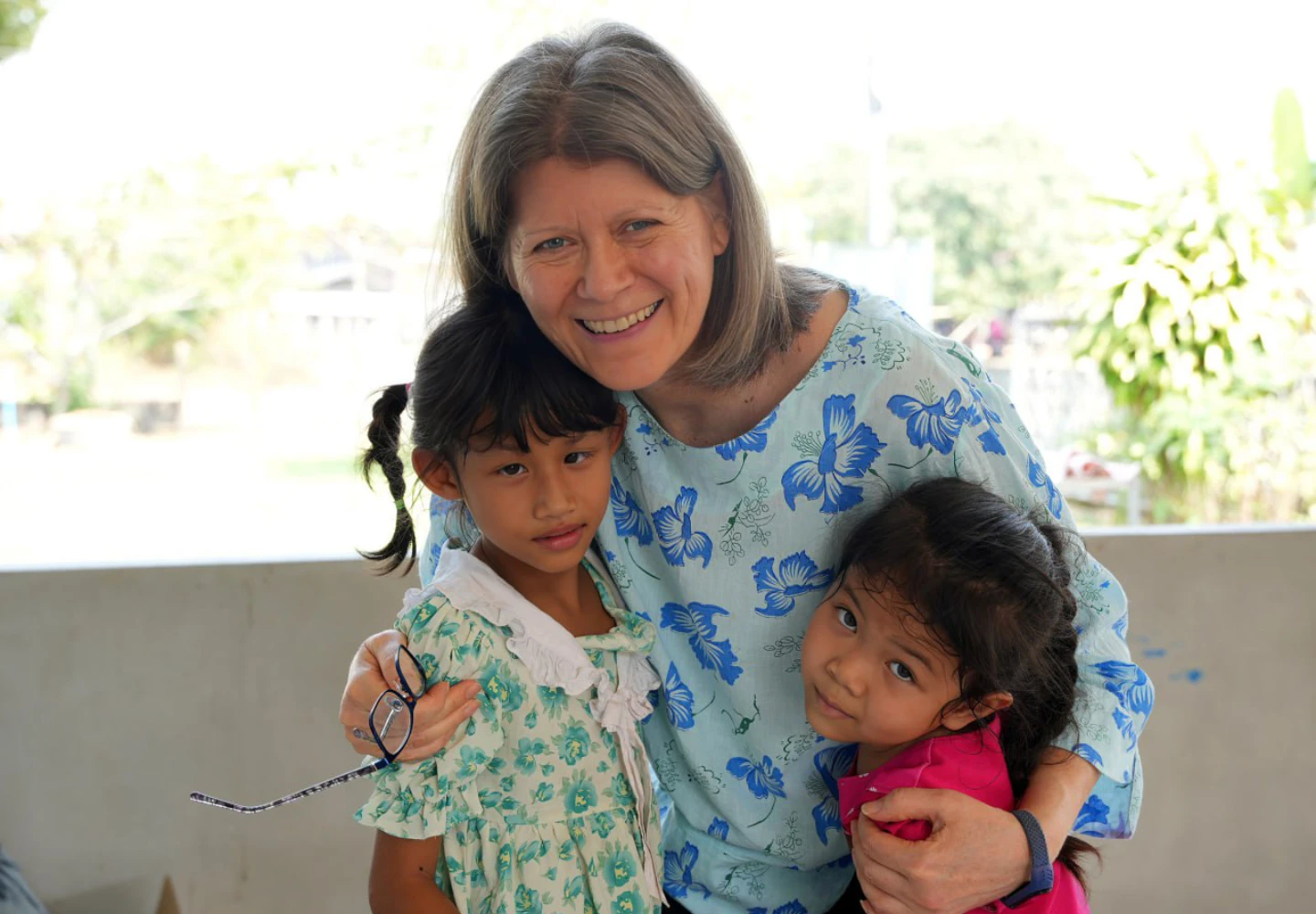 Lynette hugging two Children and smiling